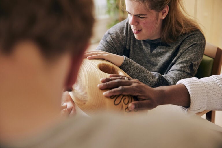 an autistic person and two unrecognizable people holding a crdl