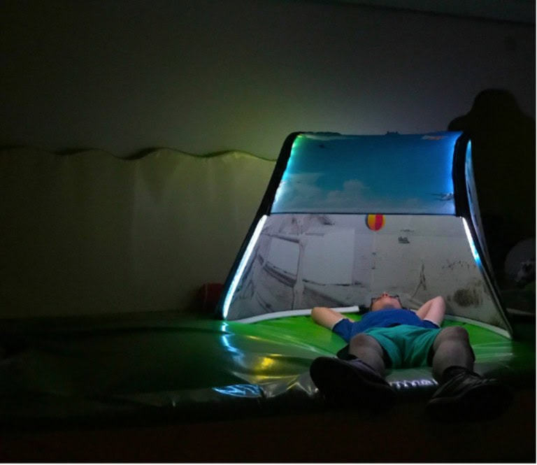 a child lying under a snoezelen tent looking at the ceiling